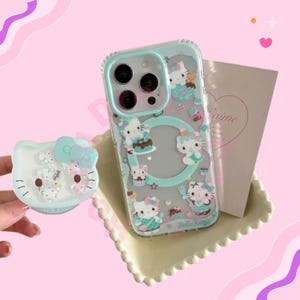 May include: Clear phone case with a mint green border and Hello Kitty illustrations. The case features Hello Kitty characters with cakes and cupcakes. A matching Hello Kitty phone grip is also visible.