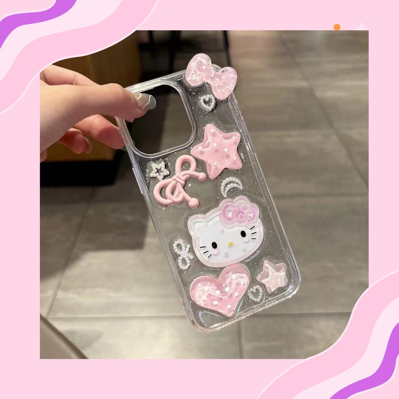 May include: Clear phone case decorated with pink bows, stars, hearts, and a Hello Kitty character. The case has a glittery appearance and is designed for a smartphone. The case is held by a person.