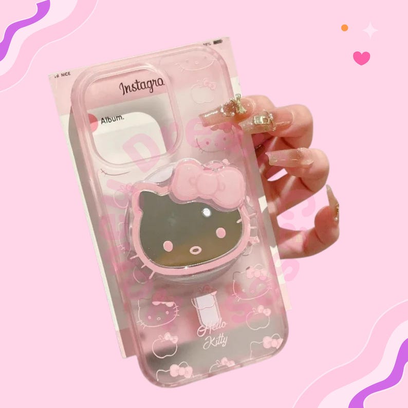 May include: A clear pink phone case featuring a Hello Kitty design. The case has a pop-up grip with a Hello Kitty face and bow. The words "Instagra" and "Hello Kitty" are visible on the case.