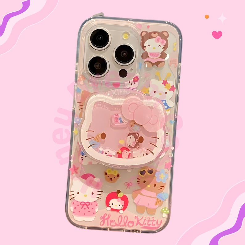 May include: Clear phone case with Hello Kitty and friends design. The case has a pink background with various Hello Kitty designs, including a large pink Hello Kitty face with a bow. Other characters and details include a bear, an apple, and the words "Hello Kitty".