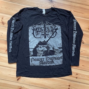 Puede incluir: Una camiseta negra de manga larga con un estampado gráfico gris de un tanque y el texto "Panzer Division Marduk" en la parte delantera. Las mangas también presentan el texto "Panzer Division Marduk" impreso en una fuente gótica.