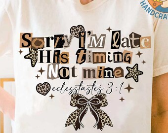 May include: Cream-colored t-shirt with the text "Sorry I'm late, His timing, Not mine, Ecclesiastes 3:1" in a mix of fonts and leopard print accents. The design includes stars, hearts, and a bow.