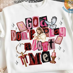 May include: White crew neck t-shirt with a graphic design. The design features the text "GOD Don't Play About ME" in a collage style with religious imagery, including Jesus, a lamb, a dove, and a cross.