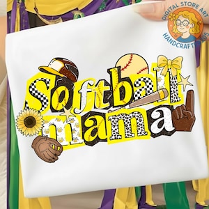 Può includere: Maglietta bianca con tema softball. Il design include le parole "Softball Mama" in giallo e nero, insieme a una palla da baseball, un guanto, un girasole e altre grafiche sportive. La maglietta è tenuta da una mano.