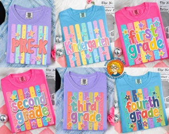 May include: A collection of colorful t-shirts, each displaying a grade level from Pre-K to Fourth Grade. The shirts feature vertical stripes and star accents, with the grade level text in a playful font. The shirts are in various colors.