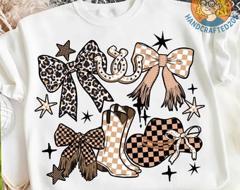 May include: White t-shirt featuring a graphic design with bows, stars, and cowboy boots. The bows have leopard print, checkered, and fringed details. The boots and hat are checkered. The word "Yeehaw" is in the design.