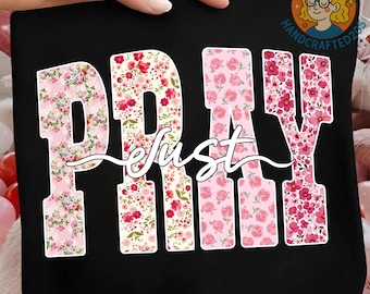 May include: Black tote bag with the word "PRAY" in large, floral-patterned letters. The word "just" is written in cursive script across the center. The floral patterns include pink and red flowers on a white background.