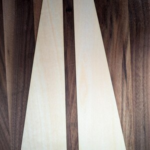 May include: Two light-colored wooden display stands with a trapezoid shape. One stand has the word "REFERENCE" etched into the wood, and the other has "HISTORY & CULTURE". The stands are on a dark wood surface.