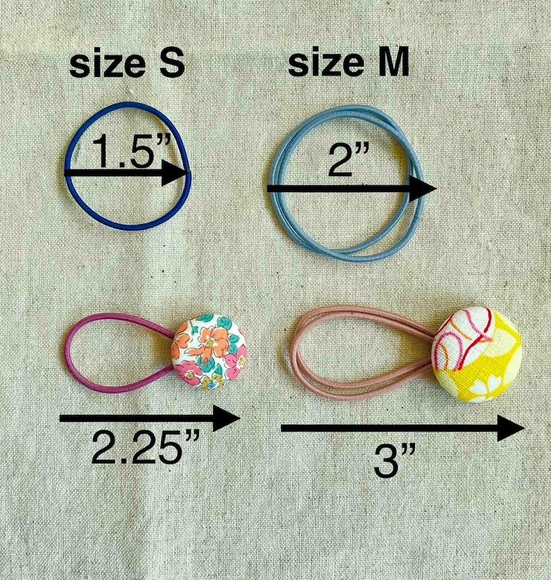 May include: An assortment of hair ties in various sizes and styles. Includes a blue elastic band measuring 1.5 inches, a light blue band at 2 inches, and two button-adorned ties at 2.25 and 3 inches. The buttons feature floral and abstract patterns.