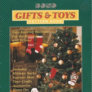 May include: A book cover with a green background and white polka dots. The title is "Gifts & Toys Pattern Book" in red and white letters. The cover features a Christmas tree decorated with ornaments and a knitted bunny rabbit.