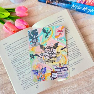 May include: A colorful sticker with a pink, blue, and green background. The sticker features a black and white illustration of a dragon with wings and the text "My Book Boyfriends Have Wings".