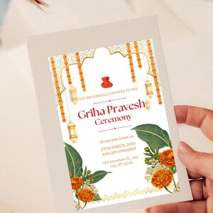 May include: A white invitation card with gold and orange accents. The card features an illustration of a traditional Indian archway with hanging lights and flowers. The text on the card reads "You're cordially invited to the Griha Pravesh Ceremony of our new home on 23th March, 2030 8:00 AM onwards 123 Anywhere St., Any City, ST 12345".