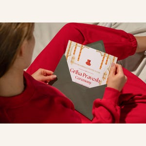 May include: A green envelope with a white invitation card inside. The invitation card has a gold and orange design with the text "You're cordially invited to the Griha Pravesh Ceremony".