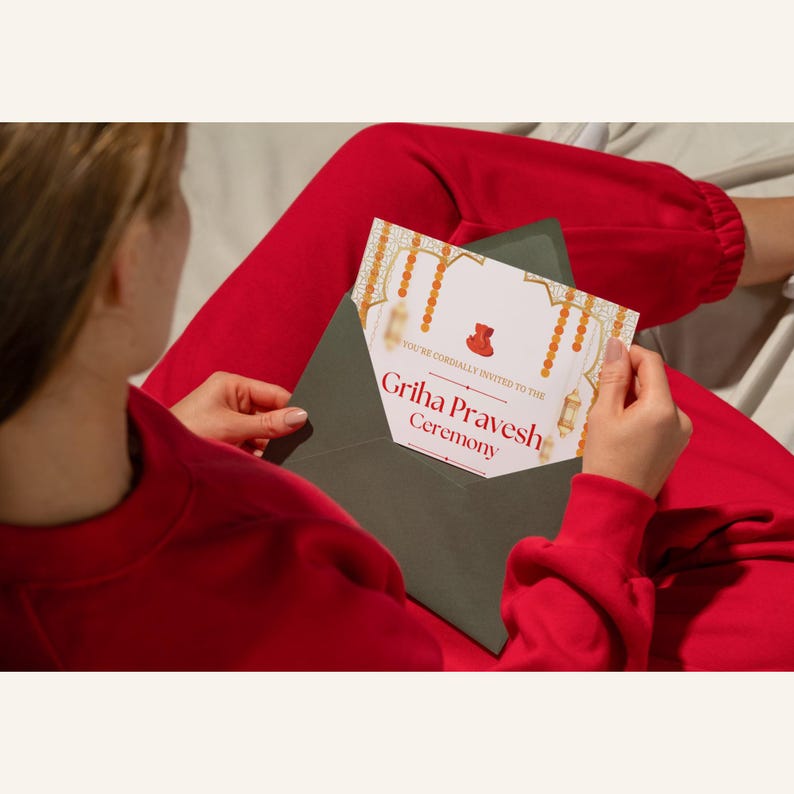 May include: A green envelope with a white invitation card inside. The invitation card has a gold and orange design with the text "You're cordially invited to the Griha Pravesh Ceremony".