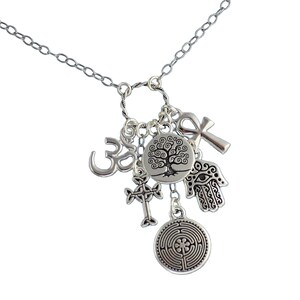 Könnte beinhalten: Silberne Halskette mit mehreren Anhängern, darunter ein Lebensbaum, ein Om-Symbol, ein keltisches Kreuz, eine Hamsa-Hand, ein Ankh und ein Labyrinth.