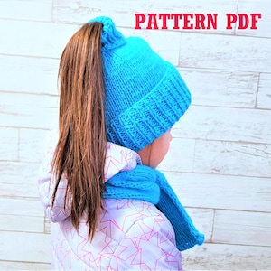 Puede incluir: Un gorro azul tejido con abertura para coleta, combinado con una bufanda a juego. El gorro tiene un borde acanalado y se usa con una chaqueta blanca con un estampado de estrellas rosas. El texto "PATTERN PDF" se muestra en rojo.