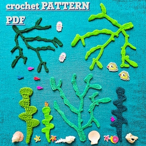 May include: A crochet pattern PDF featuring various crocheted sea plants in shades of dark green, lime green, and teal. The arrangement includes small decorative buttons shaped like jellyfish, pufferfish, snails, and starfish, plus several seashells.