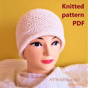 May include: A cream-colored knitted hat with a textured pattern is displayed on a mannequin. The hat is round with a folded brim. Text on the image reads "Knitted pattern PDF". The background is a solid yellow.