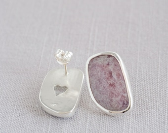 May include: A pair of silver earrings with a pink and white stone set in each. The earrings have a heart-shaped cutout on the back.