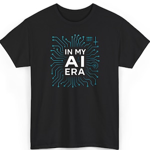May include: Black t-shirt with a teal circuit board design and the words "IN MY AI ERA" in white. The design features a square grid and a circular element within the circuit board. The shirt is a short-sleeved crew neck.
