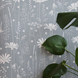 Carta da parati Daisy Meadow in 'moonrise' di Hannah Nunn, un rivestimento murale blu scuro con una stampa di un prato estivo di margherite, campanule ed erbe