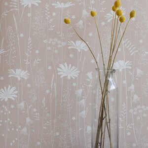 Daisy Meadow Tapete in 'Dusk' von Hannah Nunn, eine zartrosa, blumige Wiesen-Tapete mit Gänseblümchen, Harebellen und Gräsern
