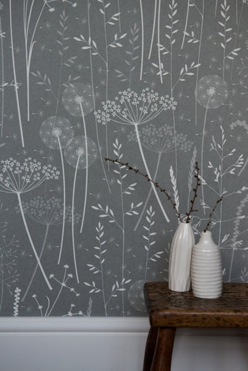 A dark grey wallpaper with a white print of grasses and dandelion clocks