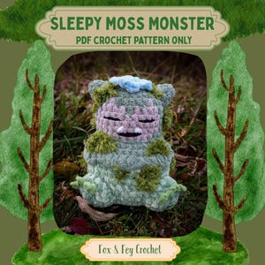 Może przedstawiać: Szydełkowy Sleepy Moss Monster w odcieniach zieleni, lawendy i niebieskiego. Pluszowa figurka ma zamknięte oczy i detale przypominające mech. Obraz zawiera tekst "Sleepy Moss Monster PDF Crochet Pattern Only" i "Fox & Fey Crochet."