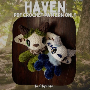 Può includere: Due creature di peluche all'uncinetto con grandi occhi e corna. Uno è verde e marrone, l'altro è bianco e blu. Il testo "HAVEN PDF CROCHET PATTERN ONLY" è in alto. Il logo Fox & Fey Crochet è in basso.