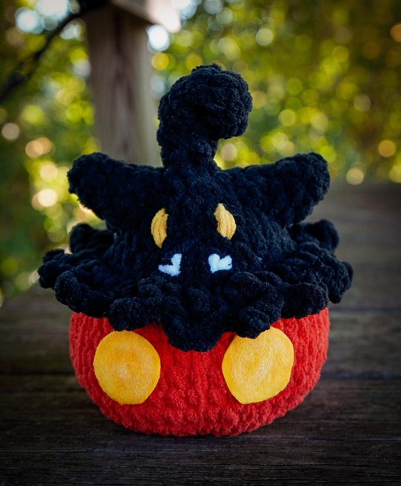 Puede incluir: Un peluche hecho a mano con ganchillo con forma de personaje de dibujos animados. El juguete presenta una cabeza negra con detalles amarillos y un cuerpo rojo con dos grandes c&iacute;rculos amarillos. El peluche est&aacute; hecho de hilo suave.