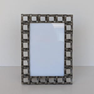 May include: A rectangular silver-toned picture frame with a woven design. The frame has a white interior and is suitable for displaying a photograph or artwork. The frame is made of metal and has a classic, elegant appearance.