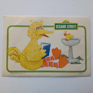 May include: A rectangular poster featuring Big Bird from Sesame Street reading a blue book while sitting next to a gray birdbath with a small yellow bird perched on the edge. The green-bordered print includes the Sesame Street logo in the corner.