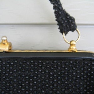 May include: A black beaded evening bag with a gold clasp and chain strap.