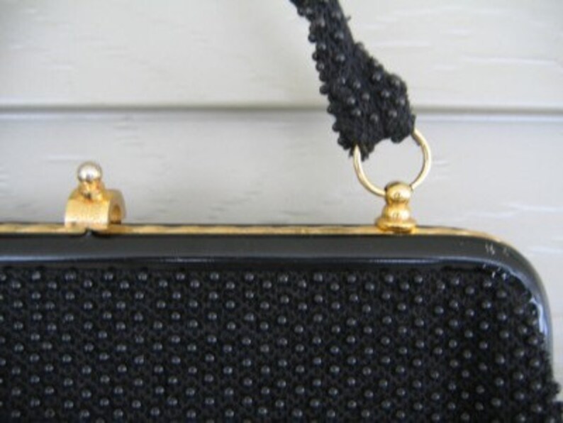 May include: A black beaded evening bag with a gold clasp and chain strap.