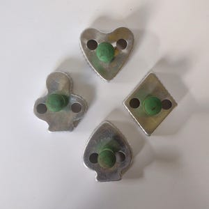 Könnte beinhalten: Vier antike Keksausstecher in Form von Spielkarten-Symbolen: Herz, Kreuz, Pik und Karo. Jeder Ausstecher hat einen grünen Holzgriff.