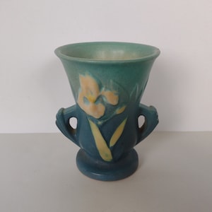 May include: A blue and yellow ceramic vase with two handles and a floral design. The vase is in the shape of an urn.