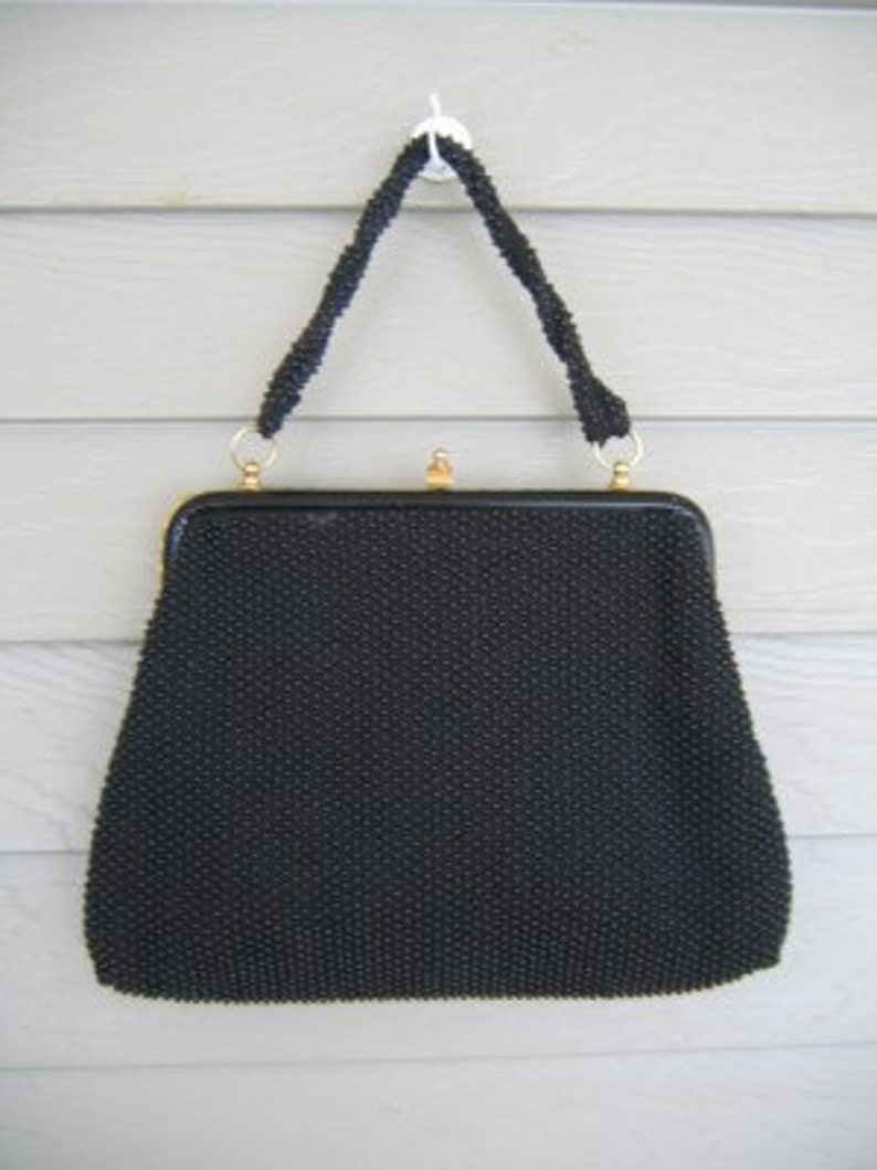 May include: A black beaded evening bag with a gold clasp and a black chain strap.