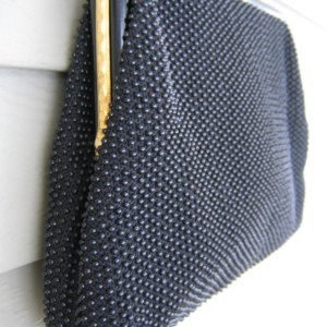 May include: A black beaded evening bag with a gold clasp and a black fabric lining.