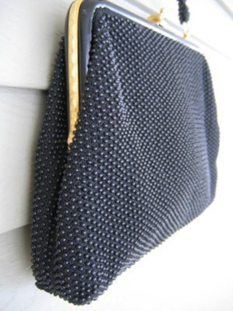 May include: A black beaded evening bag with a gold clasp and a black fabric lining.