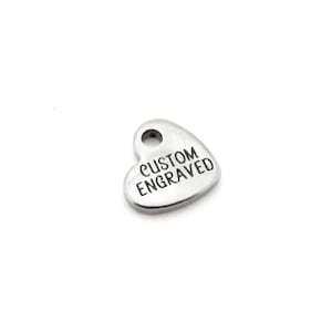 May include: A silver heart-shaped charm with the words "CUSTOM ENGRAVED" engraved on it.