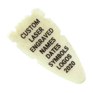 May include: A white, arrow-shaped, laser-engraved plaque with the text "CUSTOM LASER ENGRAVED NAMES DATES SYMBOLS LOGOS 2020".