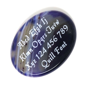 Pode incluir: Uma pedra de ágata roxa e branca com o texto "Abcd Efgh Ij Klm Opqrs Tuvw Xyz 124 456 789 Quill Font" gravado nela.