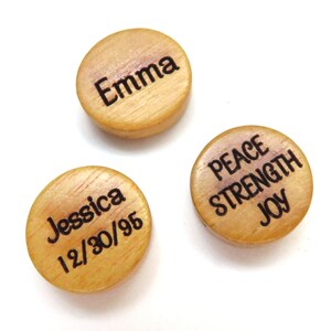 May include: Three round wooden discs with different text engraved on them. The first disc says "Emma", the second disc says "Jessica 12/30/95", and the third disc says "Peace Strength Joy".