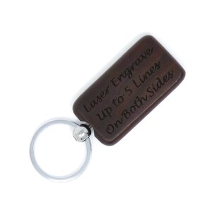 May include: A brown wooden keychain with a silver metal ring. The keychain has the text "Laser Engrave Up to 5 Lines On Both Sides" engraved on it.