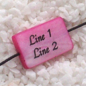 Könnte beinhalten: Eine rechteckige Perle in Pink mit dem Text "Line 1" und "Line 2" in Schwarz.