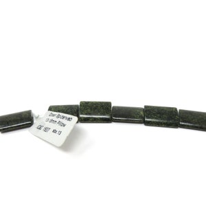 May include: A strand of dark green, rectangular, polished stone beads. The beads are approximately 1.3 cm long. The beads are labeled "Green Spiderweb 13x18mm Pillow".