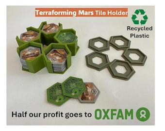 May include: Green plastic tile holder for the Terraforming Mars board game. The holder is shaped like a hexagon and has six slots for tiles. The text "Terraforming Mars Tile Holder" and "Recycled Plastic" is visible on the image. The text "Half our profit goes to OXFAM" is also visible.