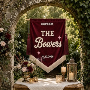 May include: A deep red velvet wall banner featuring the text CALIFORNIA, THE Bowers, and 8.20.2026 in white lettering. The banner includes two pink star icons, matching red tassels on each side, and a cream-colored fringe along the bottom edge.