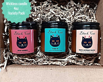 May include: A variety pack of three 4oz wickless candles in a cardboard box. Each candle has a black lid and a label with a black cat design. The labels are pink, teal, and peach, with the text "Black Cat" and scent names like "Warm Cashmere".