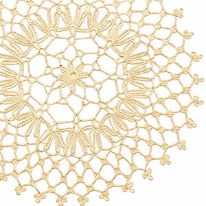 May include: Close-up of a cream-coloured, circular doily with a detailed crochet pattern. The design features floral and geometric shapes, creating an openwork texture. The doily is made of a soft, natural fibre.